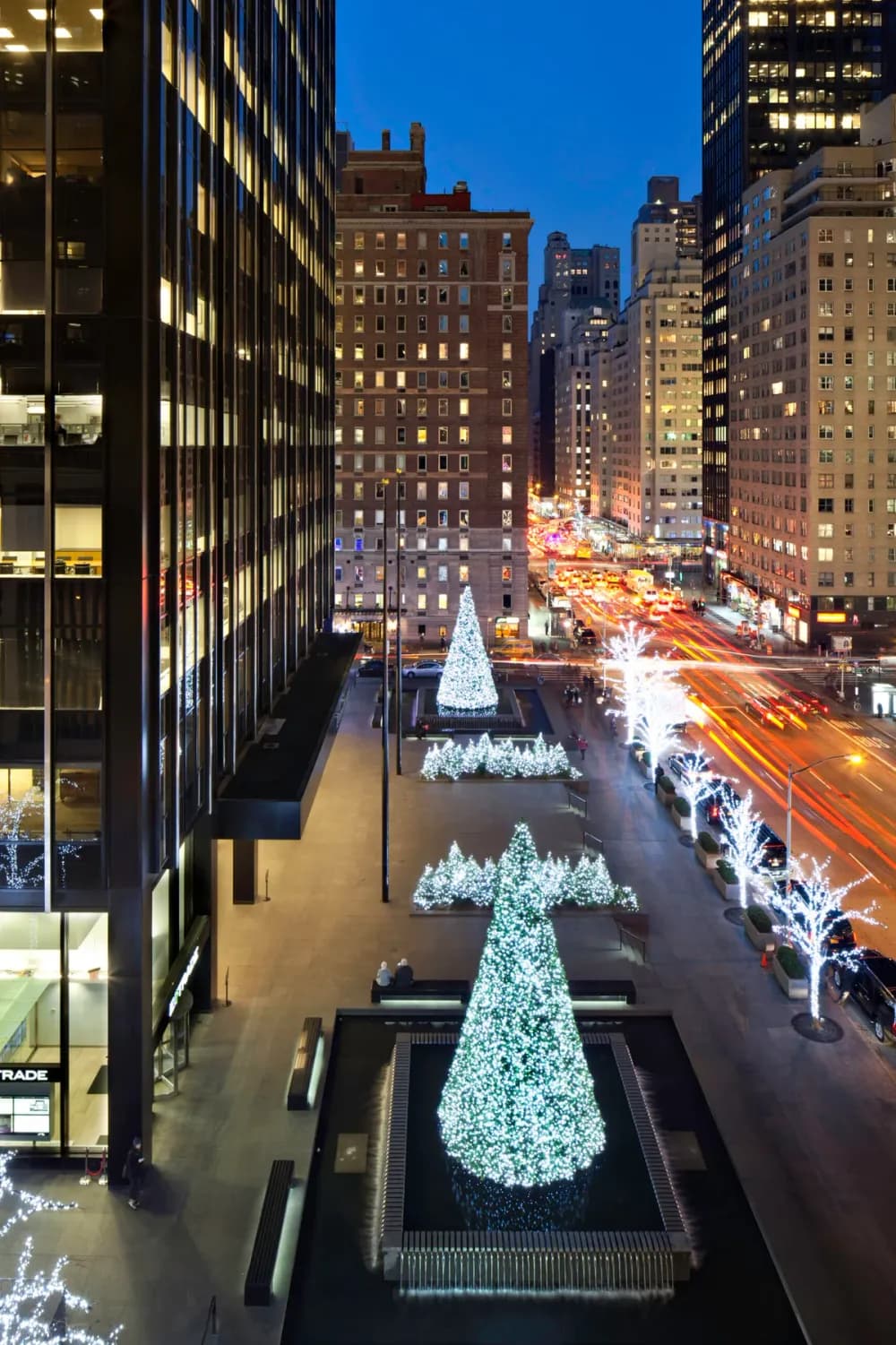 Giant commercial Christmas tree lighting a downtown square at night