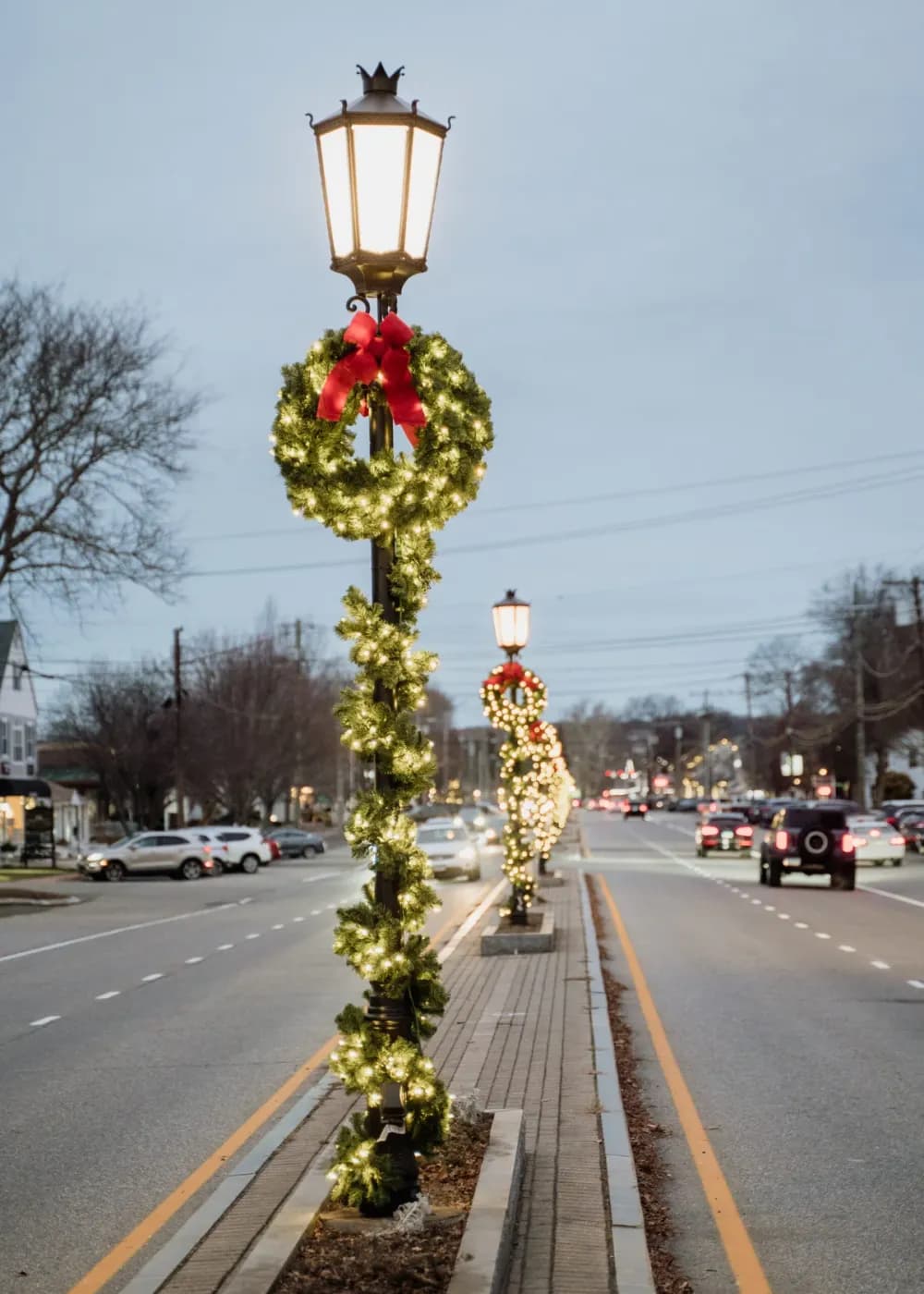 Lit garland pole wrap and street-light décor on a downtown street